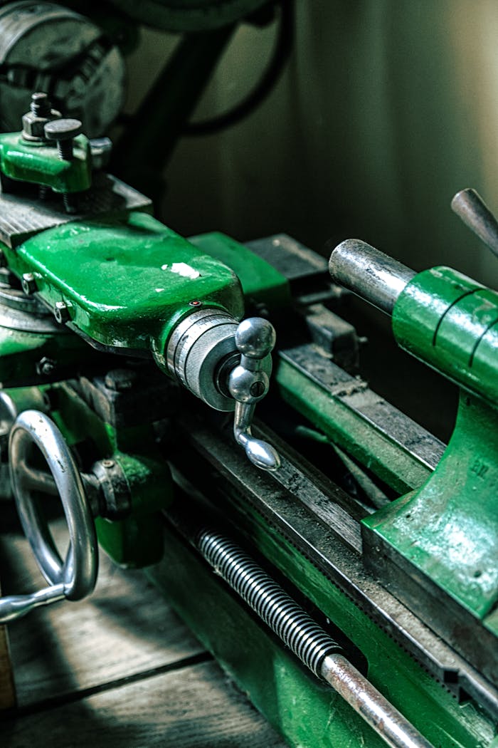 Close-up of an old green metalworking machine in an industrial setting.